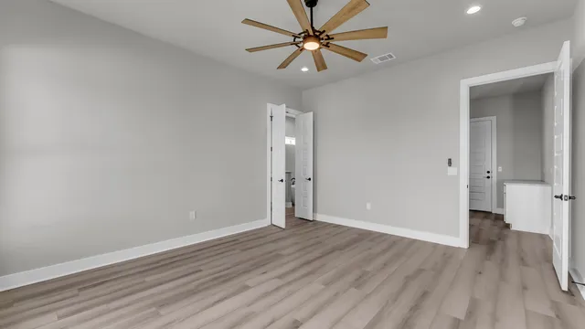 an empty room with wooden floor and a ceiling fan