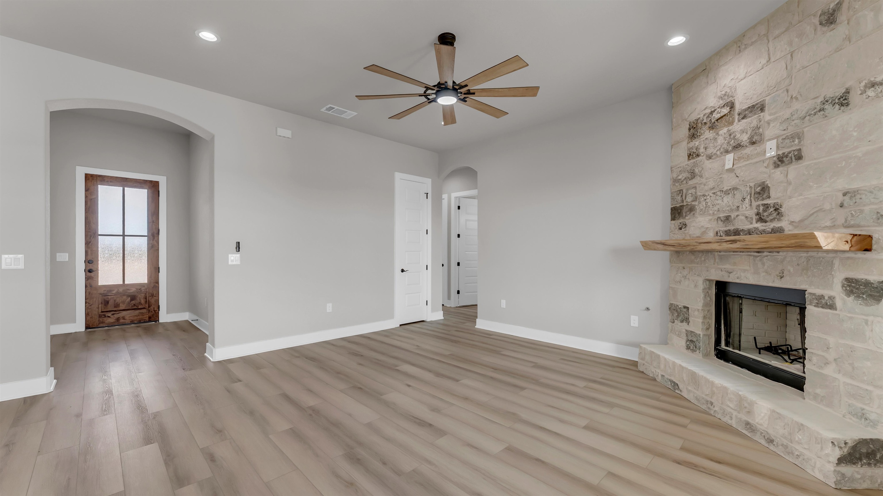 373 Prarie Point Road Bertram, TX 78605 - Photo 4 of 25 an empty room with wooden floor fireplace and windows