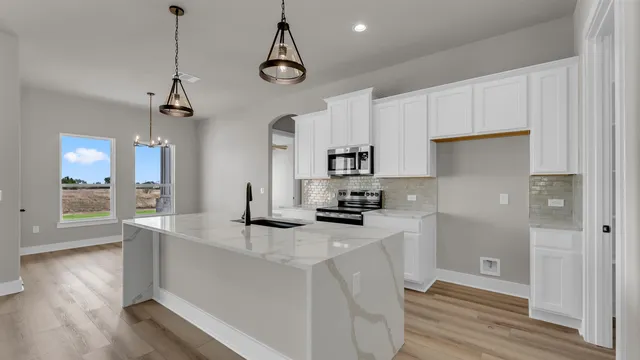 a kitchen with stainless steel appliances granite countertop a sink a stove and a wooden floors