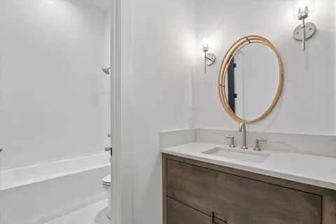 a living room with couches a dining table and a chandelier with wooden floor