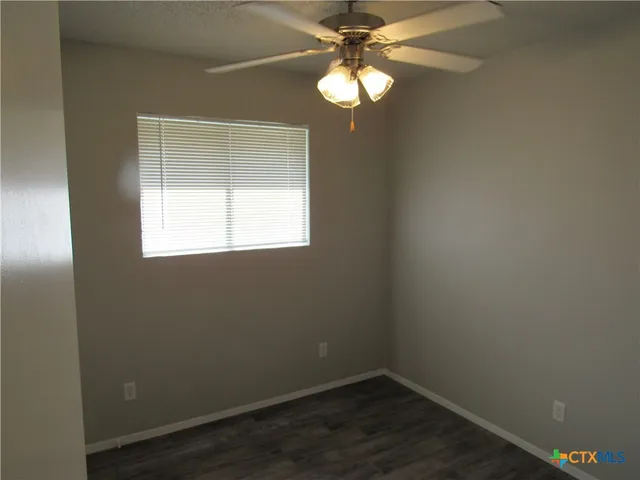 an empty room with a window and wooden floor