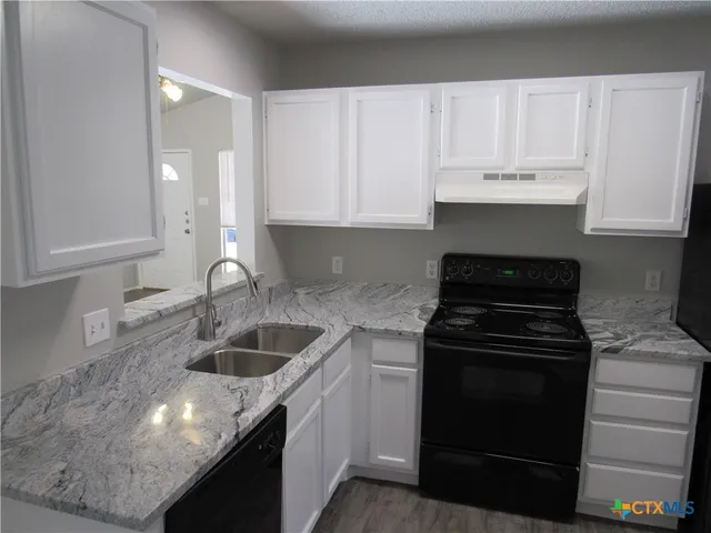 a kitchen with granite countertop white cabinets and stainless steel appliances