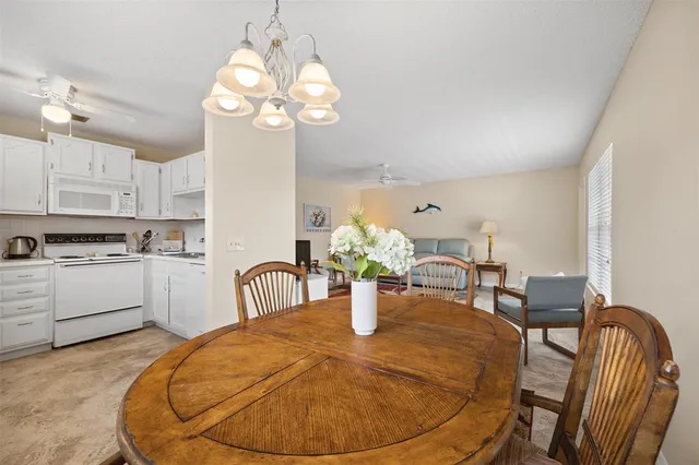 a dining room with wooden floor a chandelier a wooden table and chairs