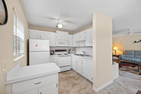 a kitchen with kitchen island white cabinets and white appliances