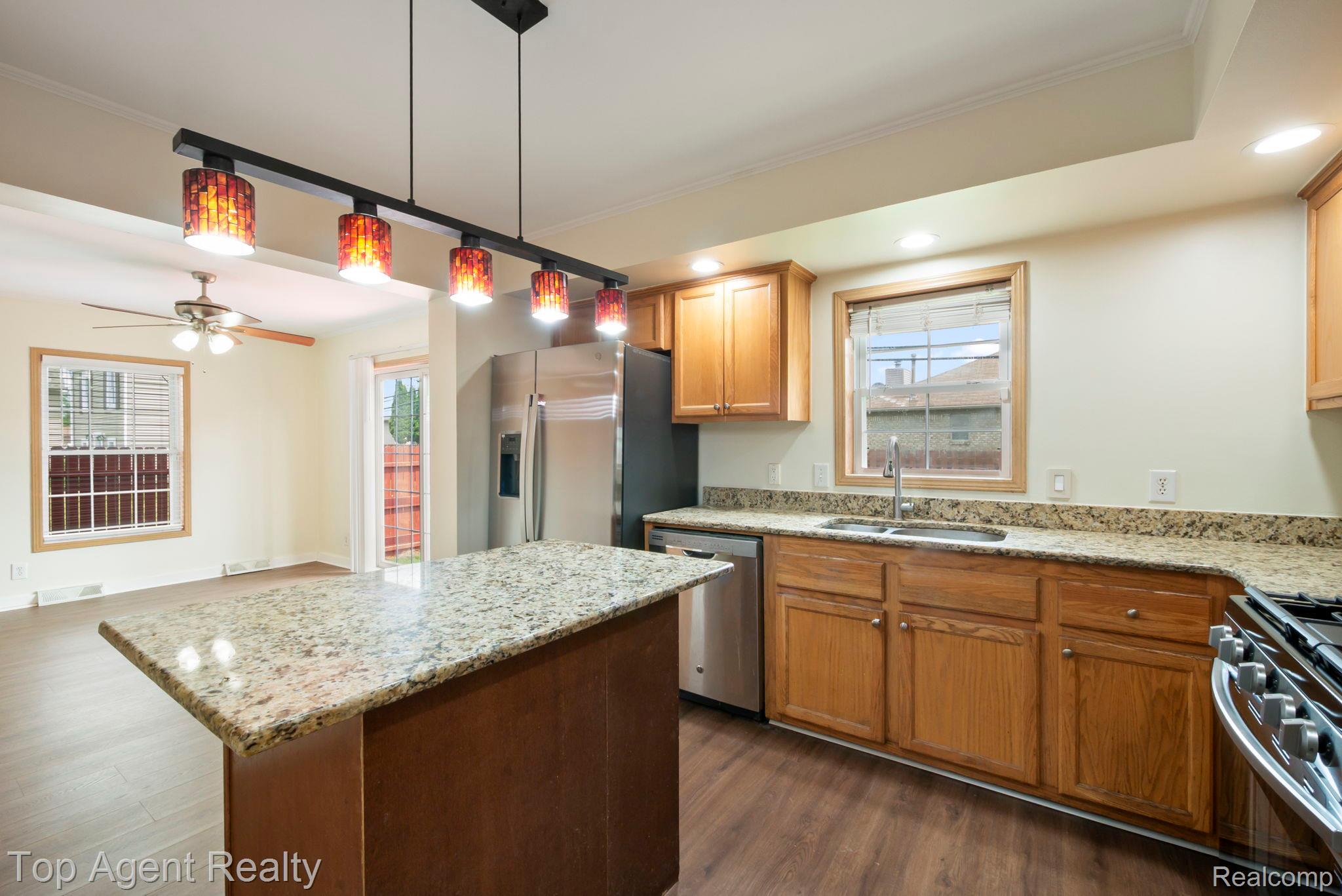 2018 John R Road Troy, MI 48083 - Photo 4 of 30 Kitchen with ornamental molding, dark wood finished floors, light stone countertops, a center island, and stainless steel appliances