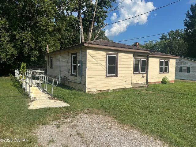 a view of a backyard with table and chairs potted plants and large tree