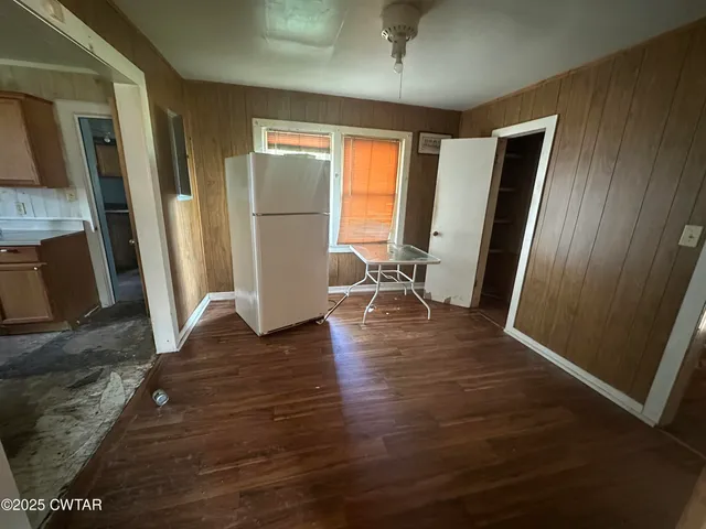 a view of a livingroom with wooden floor and a refrigerator