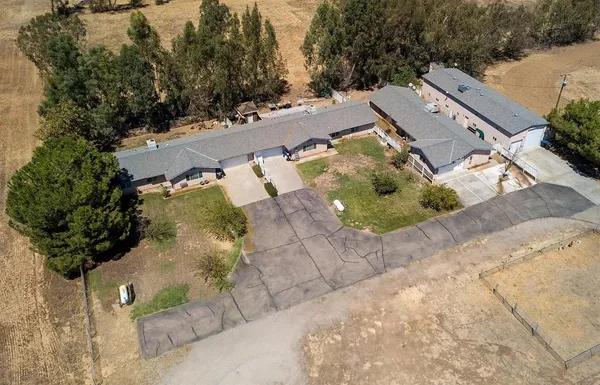 an aerial view of a house with a yard and a large tree