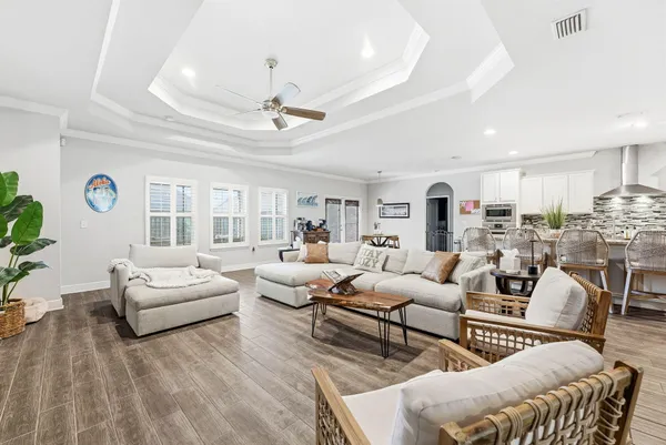 a living room with furniture kitchen view and a large window