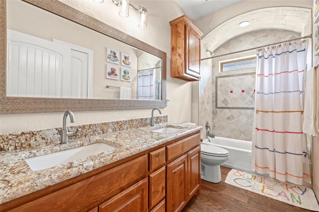 3801 Kady Ridge Abilene, TX 79606 - Photo 25 of 40 Dual vanity with granite countertop, wood-finish cabinetry, and brushed nickel fixtures