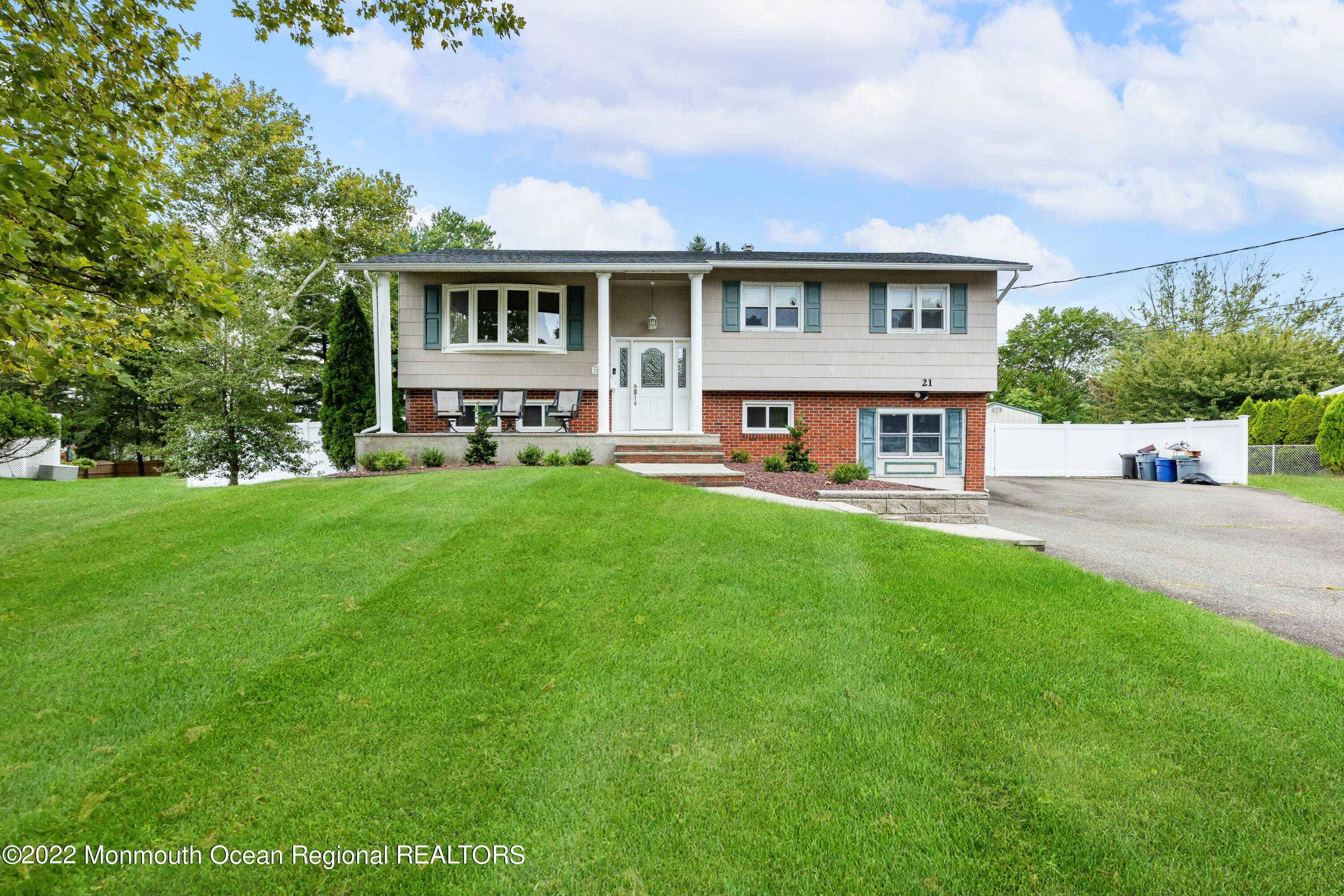 a view of a white house with a big yard and large trees
