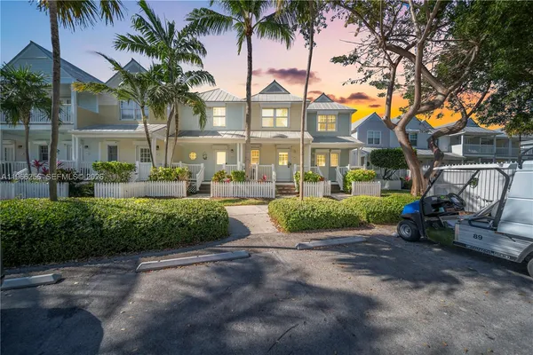 a view of multiple houses with a yard and palm trees