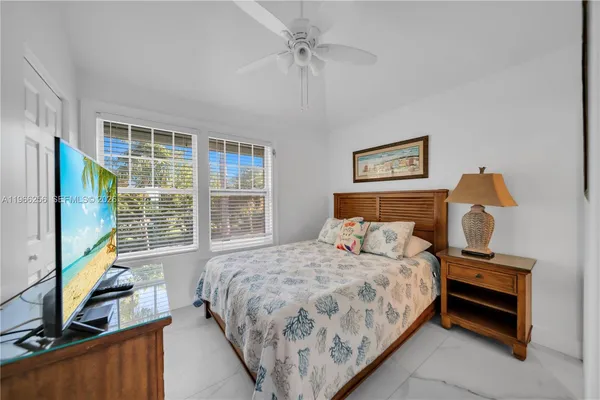 a bedroom with a bed next to a window with a flat screen tv