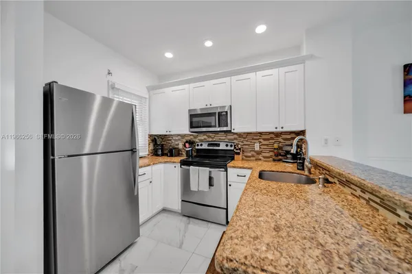 a kitchen with stainless steel appliances granite countertop a refrigerator sink and microwave