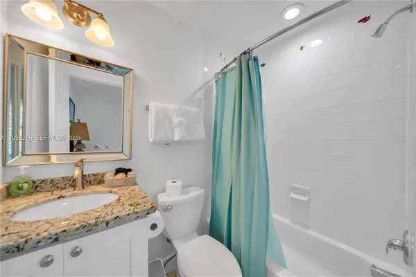 a bathroom with a granite countertop sink toilet and shower