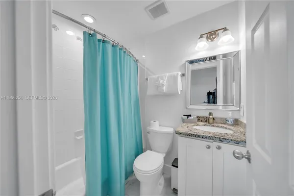a bathroom with a granite countertop sink toilet and shower