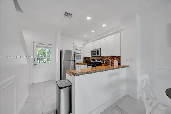 a kitchen with stainless steel appliances granite countertop a refrigerator and a stove