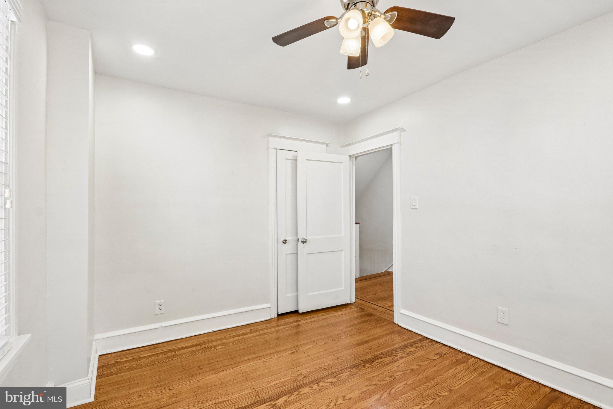 7407 Rogers Avenue Upper Darby, PA 19082 - Photo 25 of 50 an empty room with a chandelier fan and wooden floor