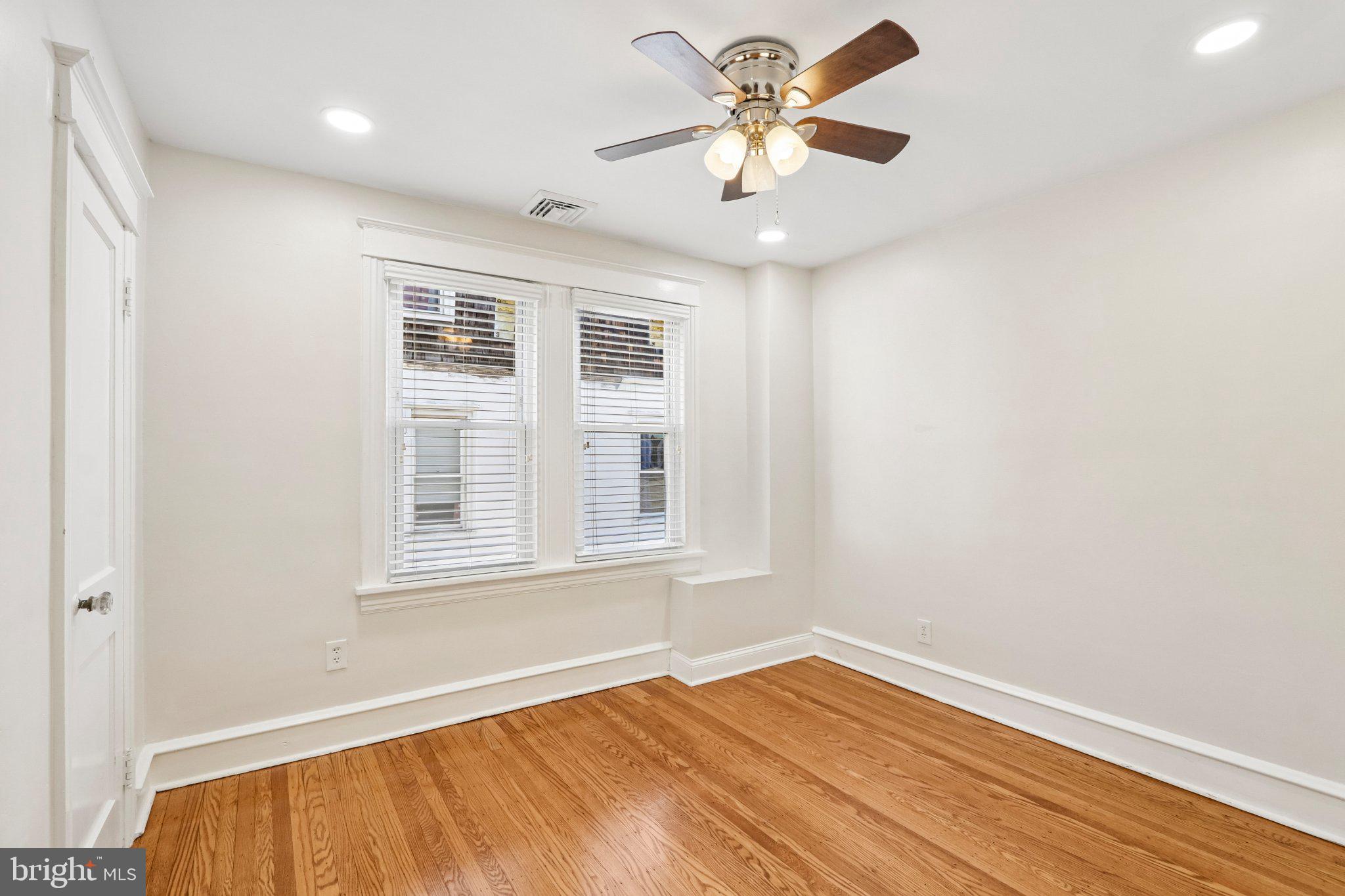 7407 Rogers Avenue Upper Darby, PA 19082 - Photo 26 of 50 an empty room with wooden floor chandelier fan and windows