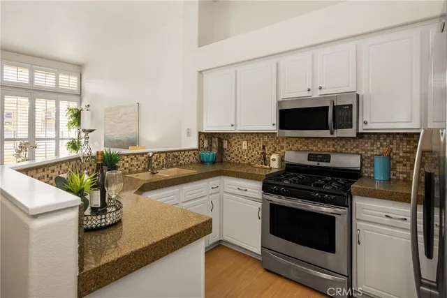 a kitchen with stainless steel appliances granite countertop a refrigerator a stove and a sink