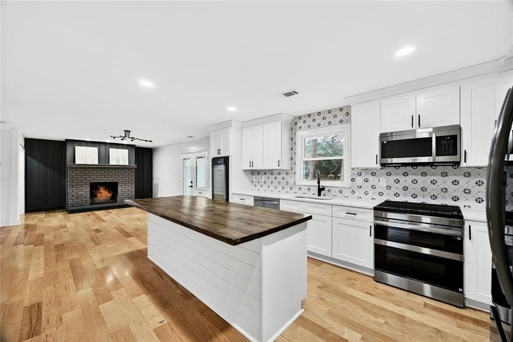 3365 Ardley Road Southwest Atlanta, GA 30311 - Photo 10 of 34 a kitchen with kitchen island granite countertop a stove top oven a sink dishwasher and a fireplace with wooden floor