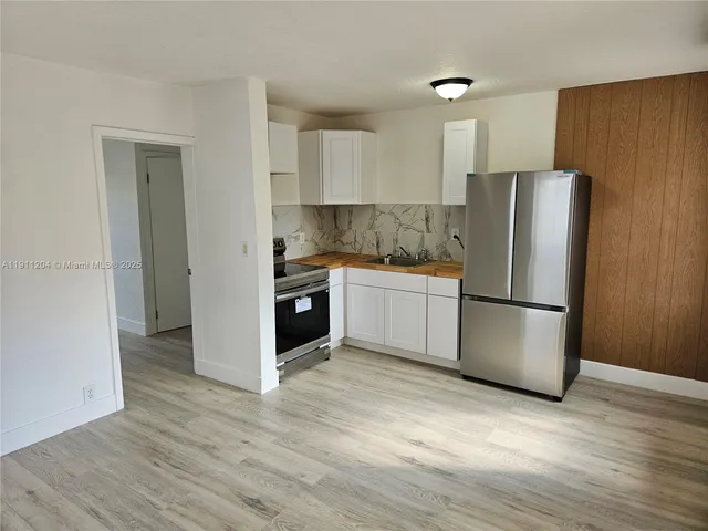 a kitchen with stainless steel appliances a refrigerator and wooden floor
