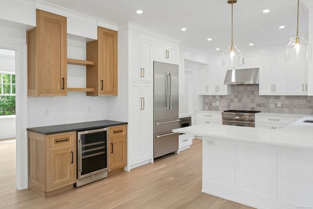 a kitchen with stainless steel appliances granite countertop a refrigerator a stove and a sink with wooden floor