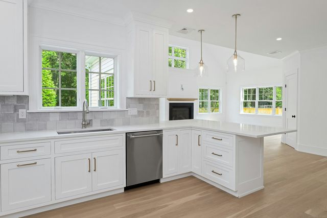 a kitchen with stainless steel appliances granite countertop a stove a sink and white cabinets with wooden floors