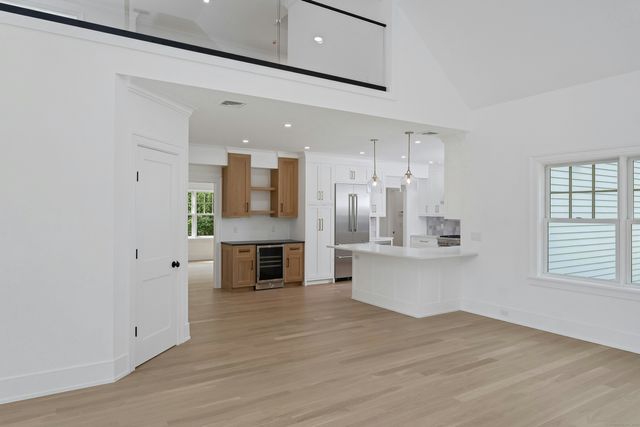 a large white kitchen with kitchen island a sink wooden floor and a refrigerator