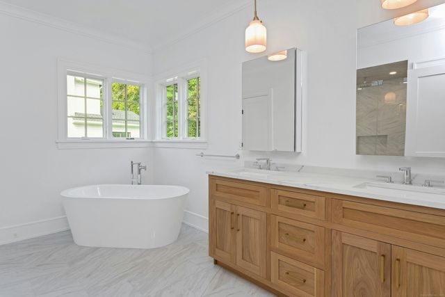 a bathroom with a white tub a sink and mirror