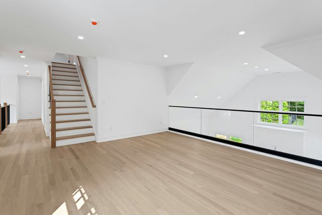 a view of an empty room with wooden floor and windows