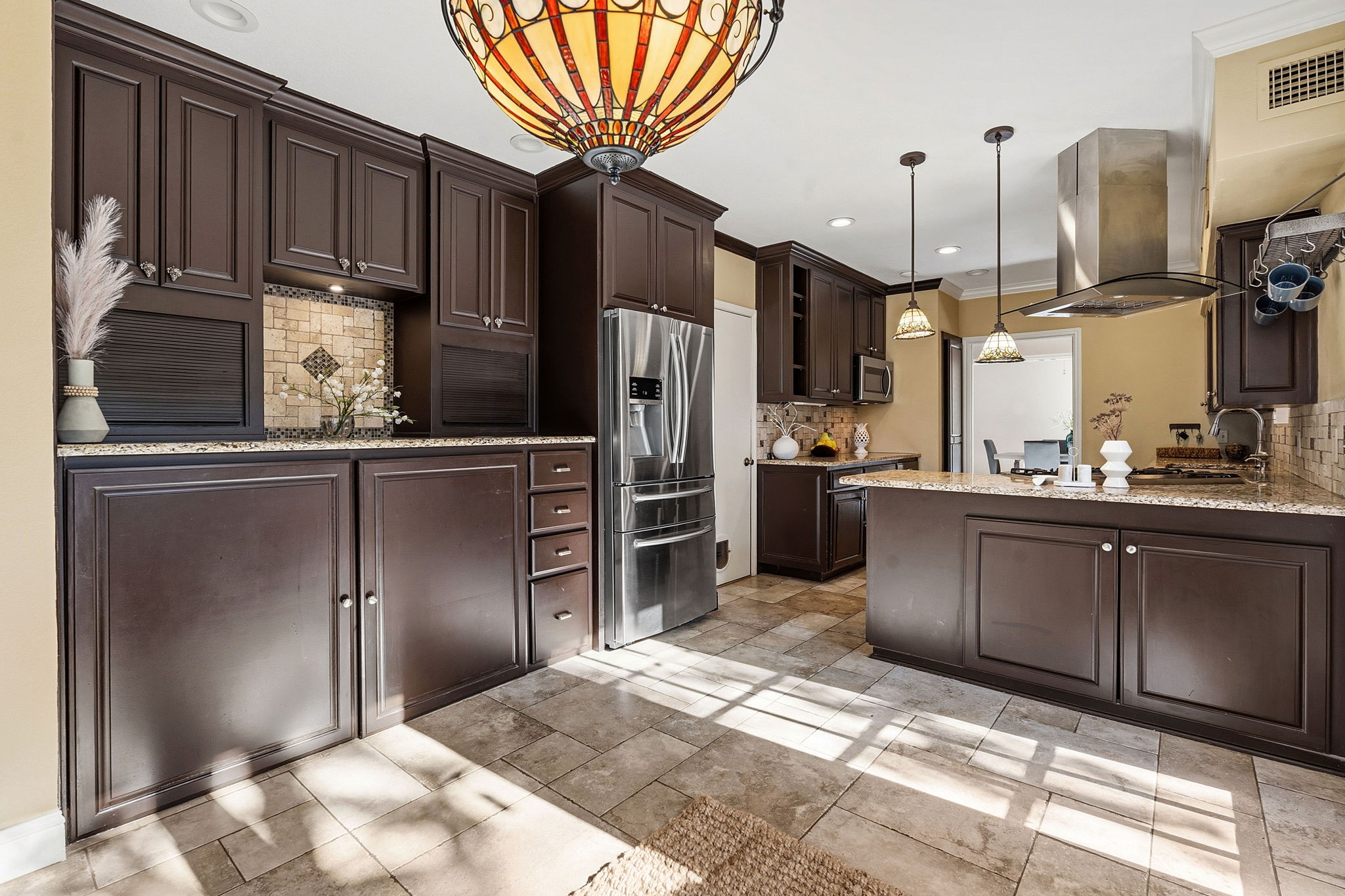 4601 Creek Ridge Austin, TX 78735 - Photo 13 of 40 Kitchen with backsplash, dark wood finish cabinets, stainless steel appliances, light stone countertops, and island range hood