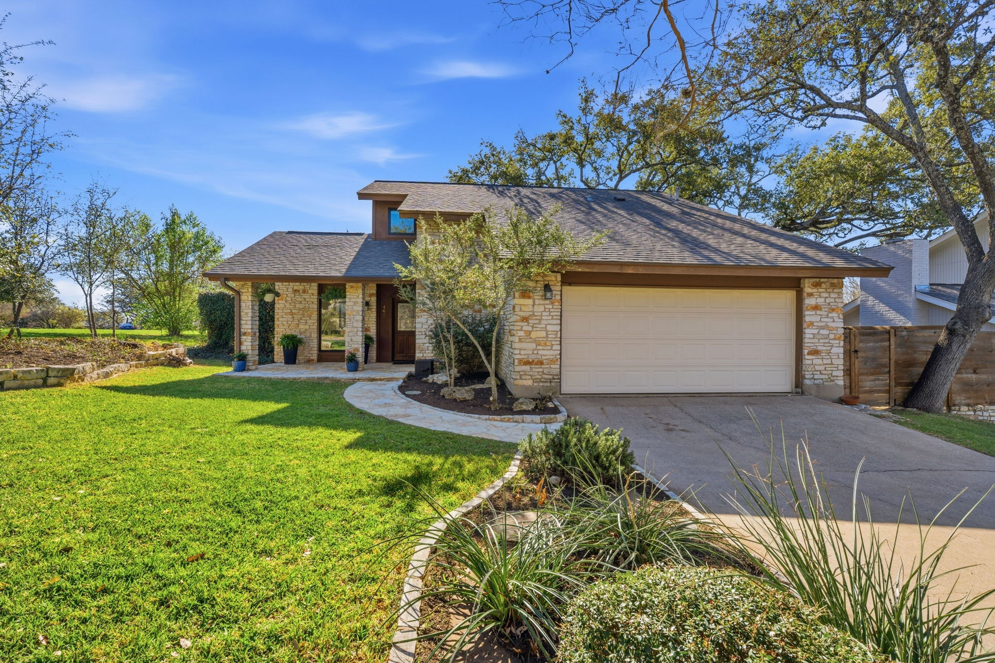 4601 Creek Ridge Austin, TX 78735 - Photo 3 of 40 View of front of house featuring roof with shingles, driveway, stone siding, and an attached garage