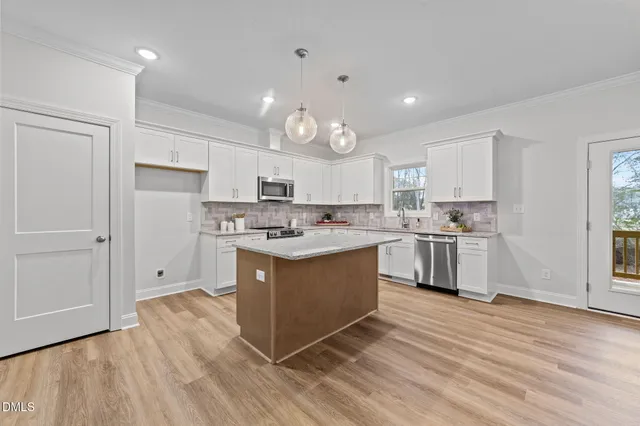 a kitchen with stainless steel appliances granite countertop a stove top oven a sink dishwasher and a refrigerator with wooden floor