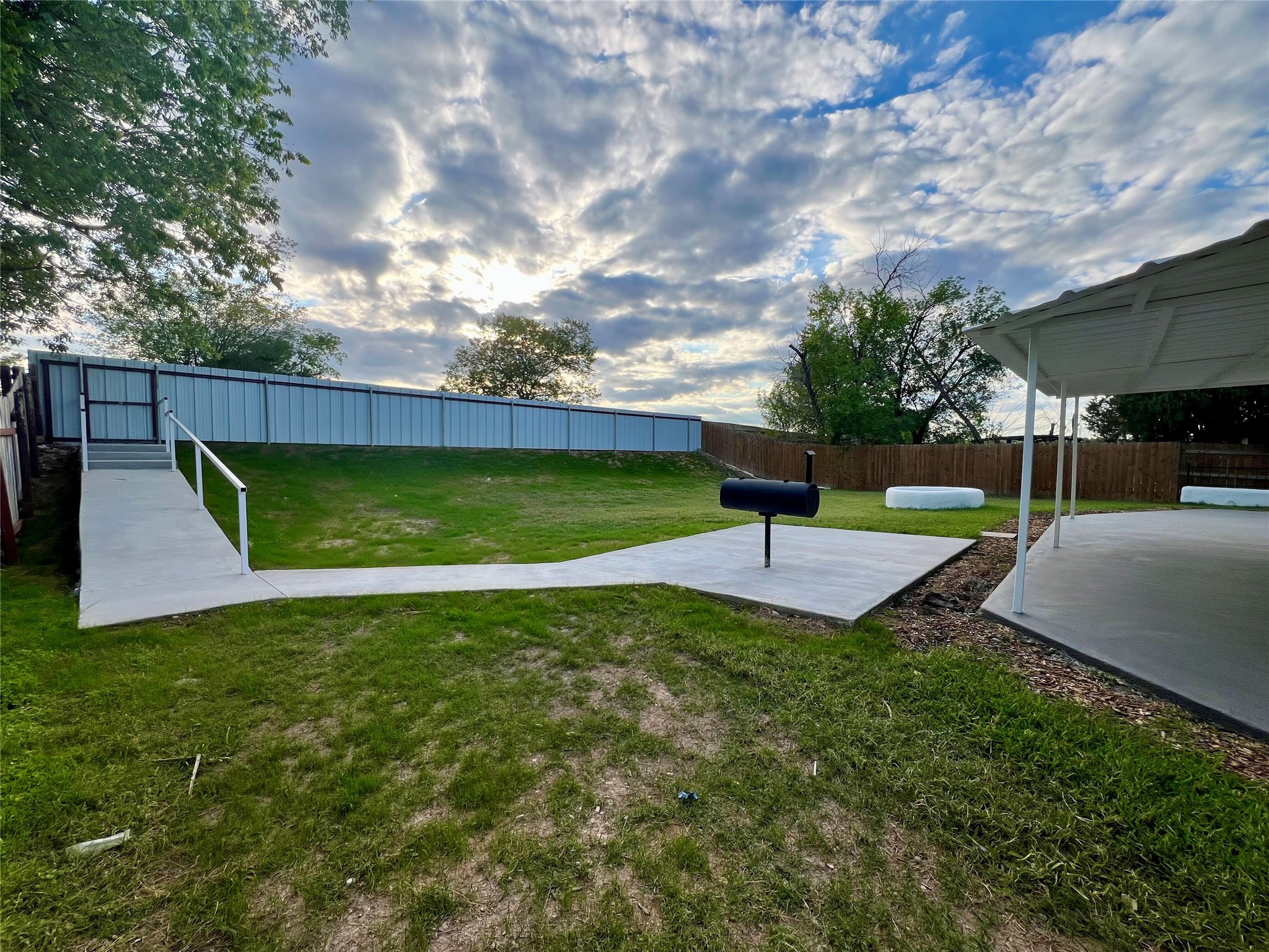 8007 Colony Loop Drive Austin, TX 78724 - Photo 6 of 40 Backyard with a covered patio, plus a separate concrete pad featuring an accessibility ramp with handrails and gated fence access.