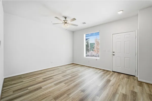 a view of an empty room with a window and wooden floor