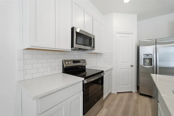 a kitchen with a sink a stove top oven and white cabinets