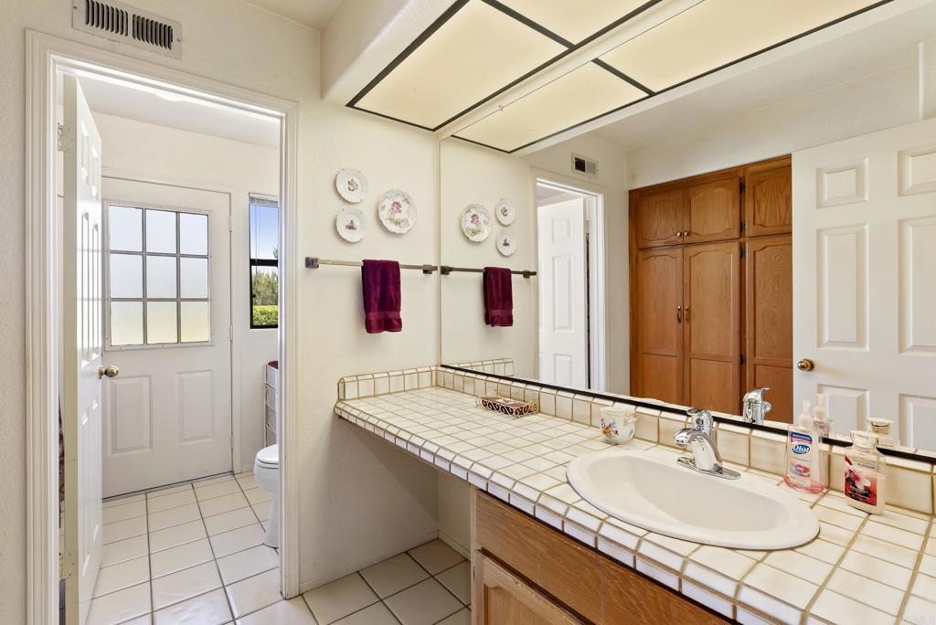 2221 Cortina Circle Escondido, CA 92029 - Photo 24 of 36 a bathroom with a granite countertop sink and a mirror