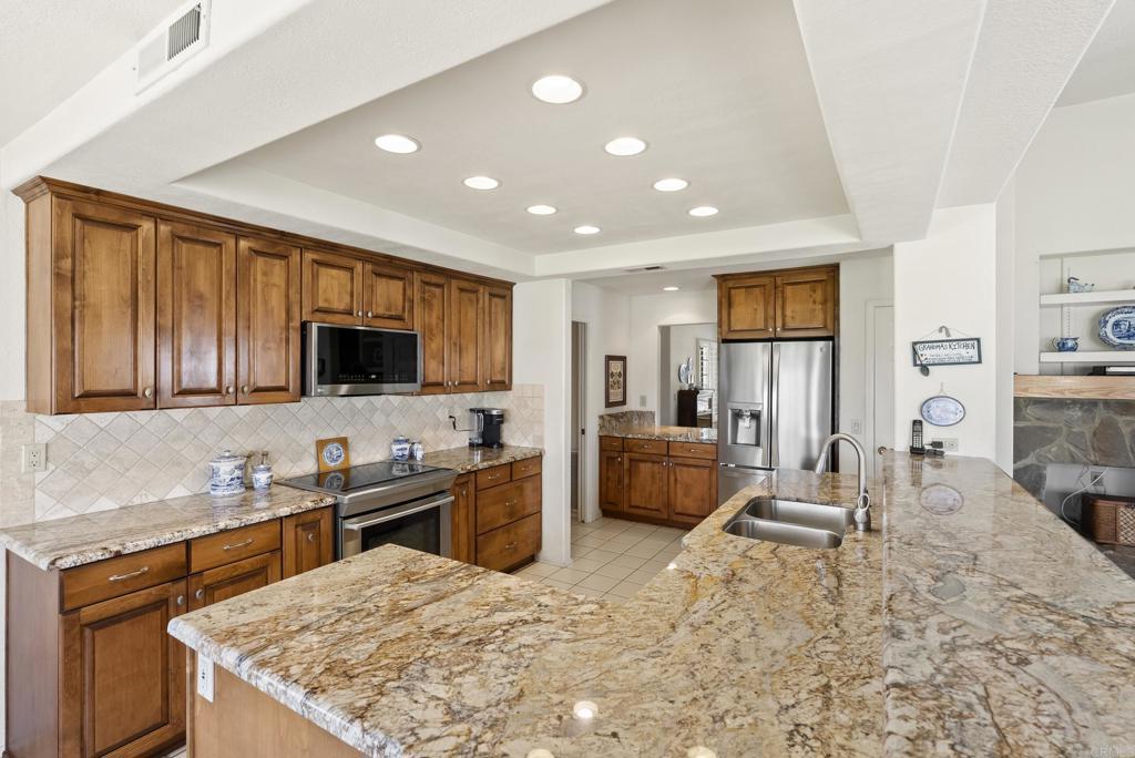 2221 Cortina Circle Escondido, CA 92029 - Photo 7 of 36 a kitchen with stainless steel appliances kitchen island granite countertop a sink and cabinets