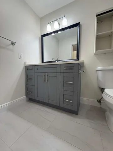 a bathroom with a granite countertop sink a toilet and a mirror