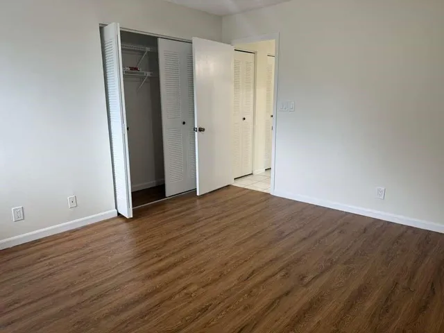 a view of an empty room with wooden floor and closet