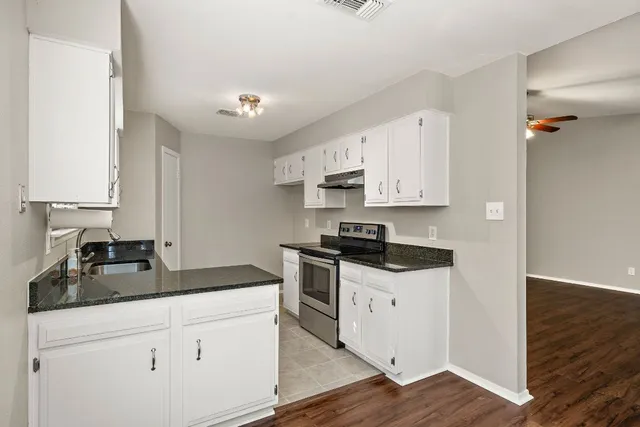 a kitchen with granite countertop a sink a stove and cabinets