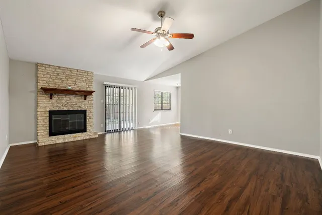 a view of an empty room with wooden floor fireplace and a window