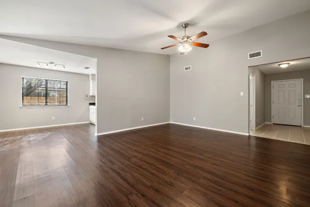 a view of an empty room with wooden floor and a window