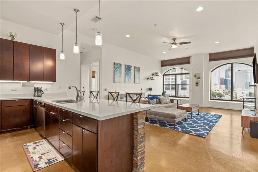 507 Sabine Street, Unit 705 Austin, TX 78701 - Photo 23 of 32 a large kitchen with kitchen island a large counter space a sink appliances and living room view