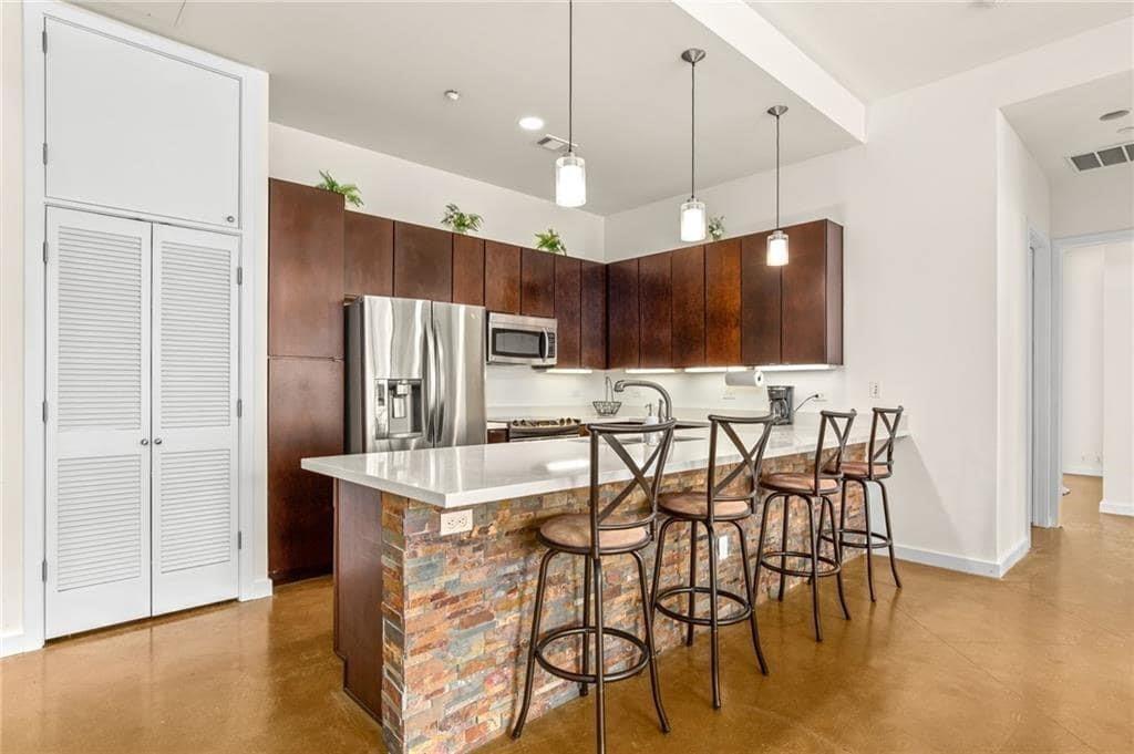 507 Sabine Street, Unit 705 Austin, TX 78701 - Photo 3 of 32 a kitchen with stainless steel appliances kitchen island granite countertop a table chairs and a refrigerator