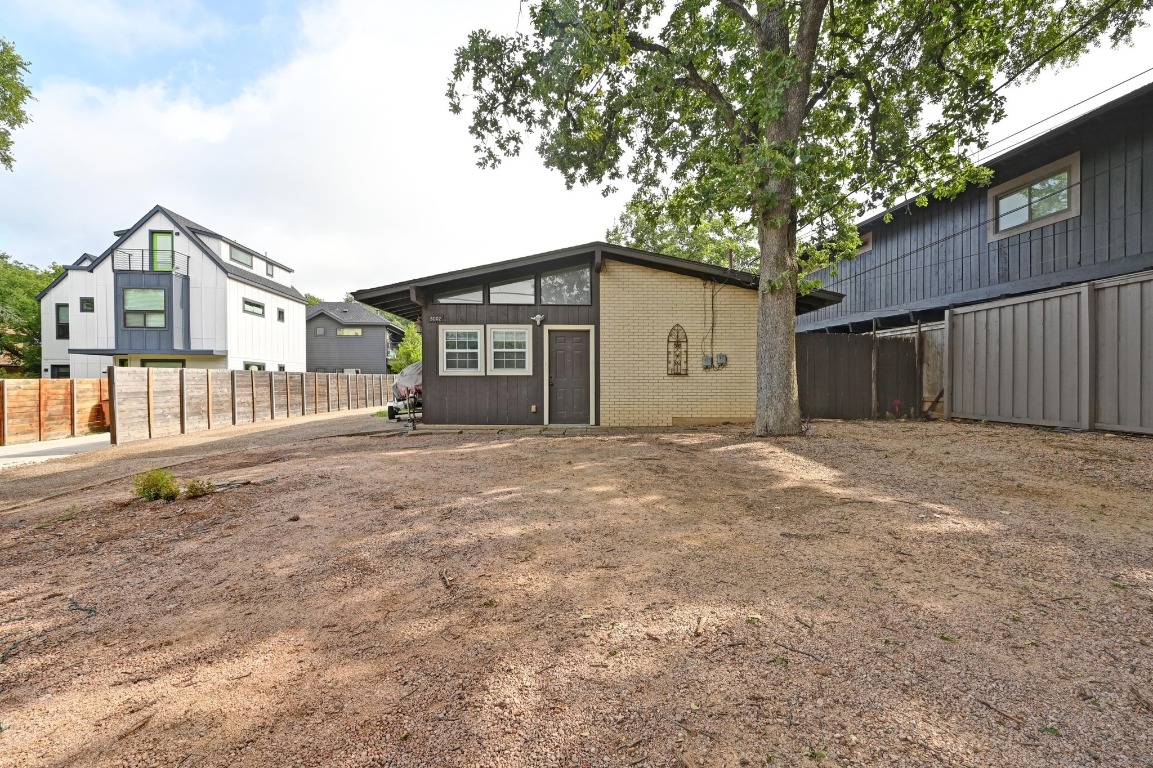 a view of a house with a large tree and wooden fence