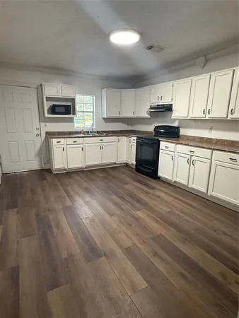 a large kitchen with cabinets wooden floor and stainless steel appliances