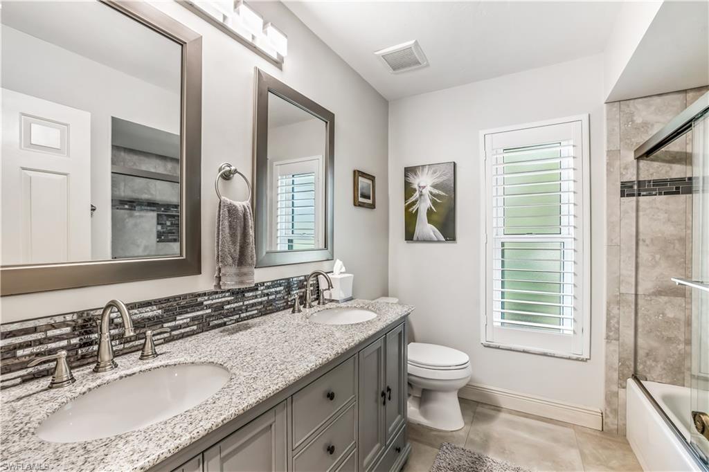 2232 Buckingham Lane Naples, FL 34112 - Photo 16 of 30 a bathroom with a granite countertop toilet a sink and a mirror