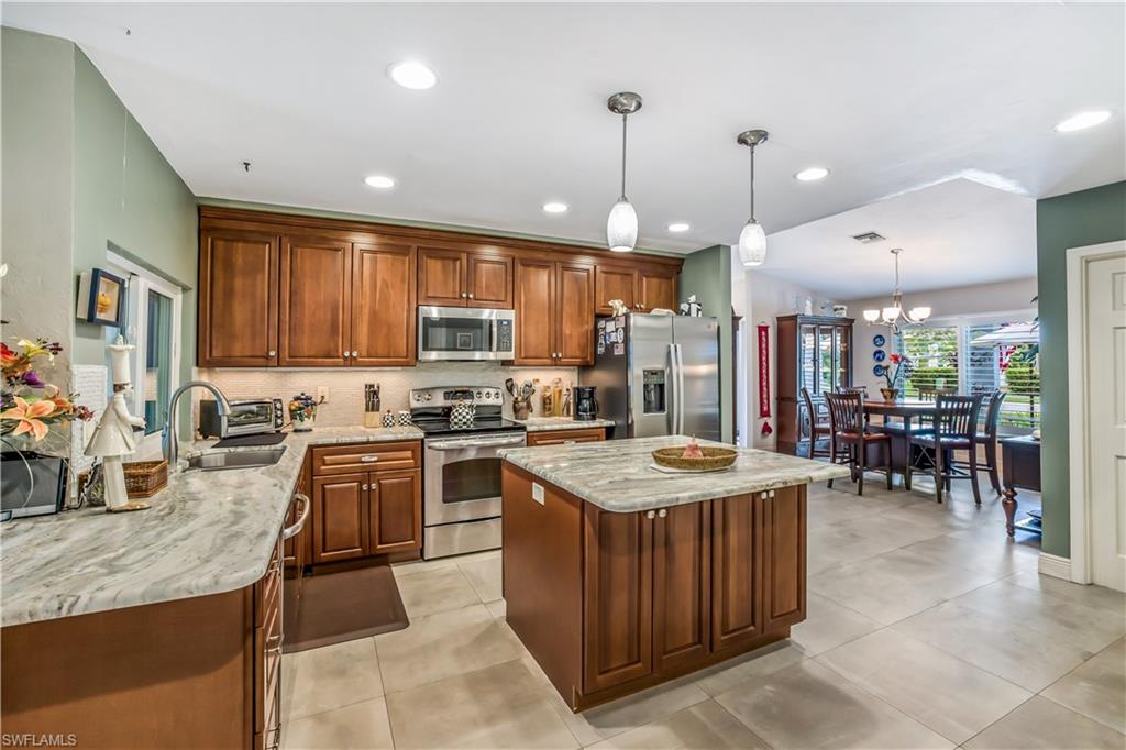 2232 Buckingham Lane Naples, FL 34112 - Photo 8 of 30 a kitchen with stainless steel appliances granite countertop wooden cabinets a sink a stove a oven a dining table and chairs